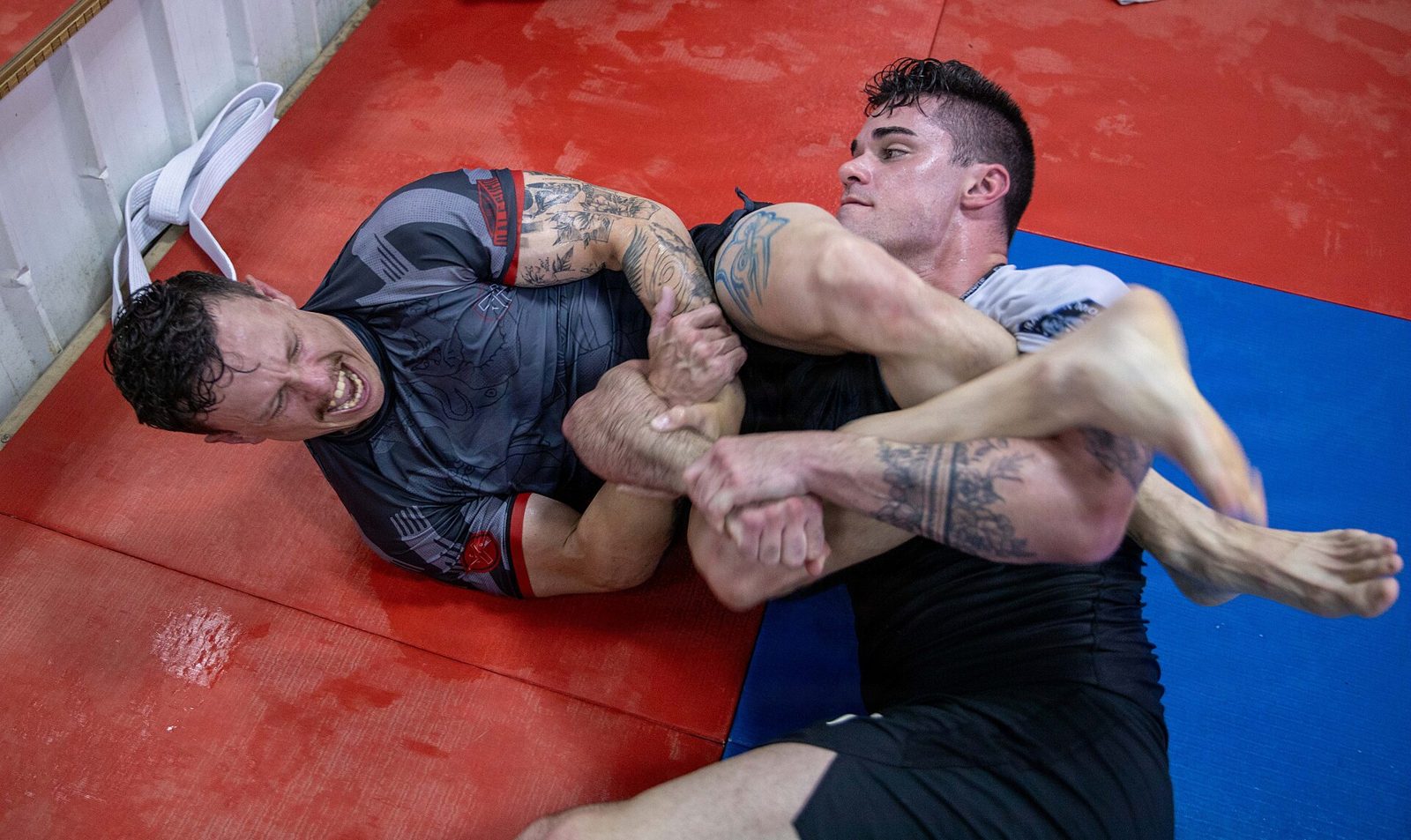 Deux pratiquants de ju-jitsu brésilien au sol, l'un tentant une clé de bras