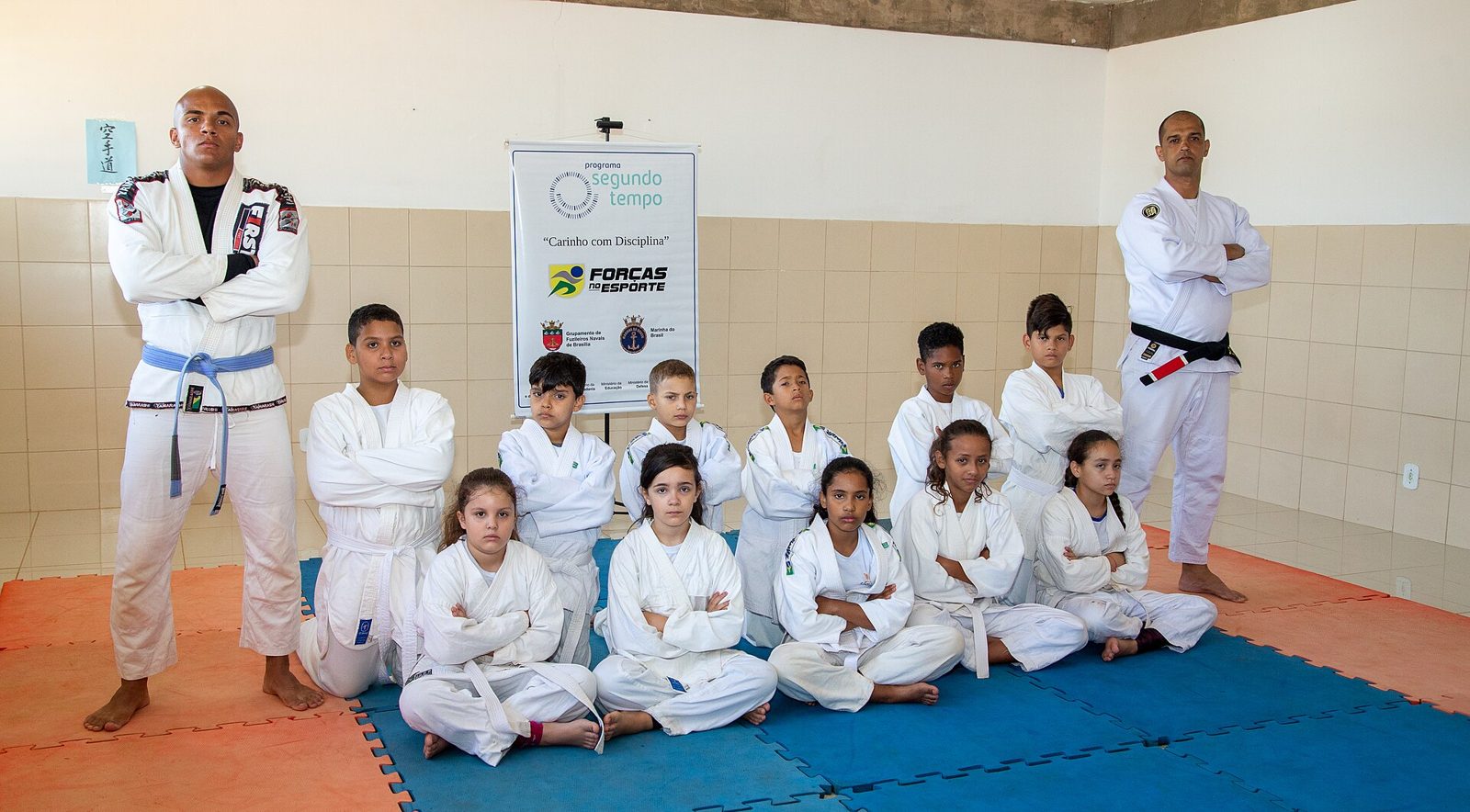 Un groupe d'enfants en kimono de ju-jitsu brésilien pose avec leurs deux professeurs