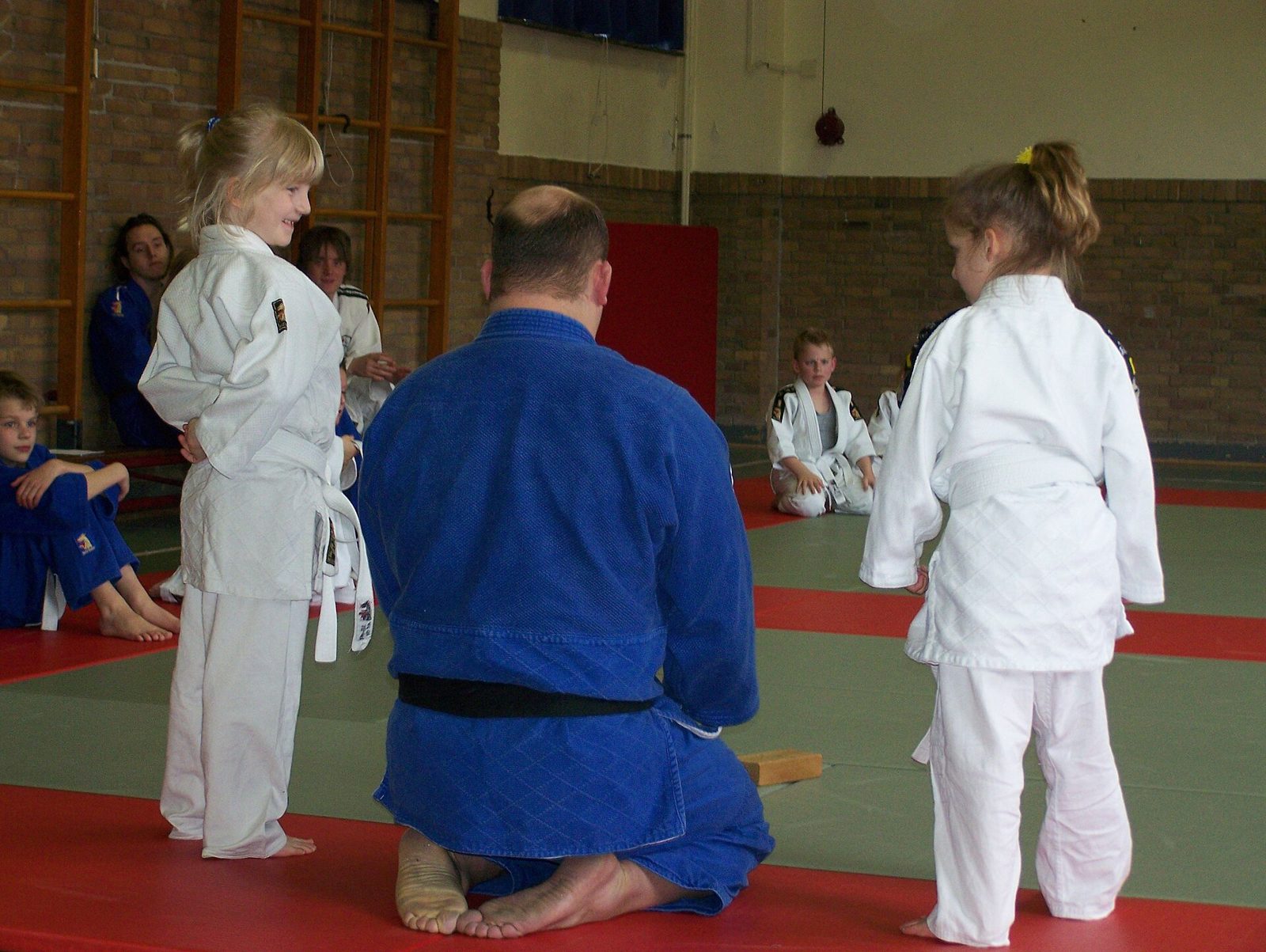 De jeunes enfants en kimono écoutent leur professeur agenouillé sur le tatami